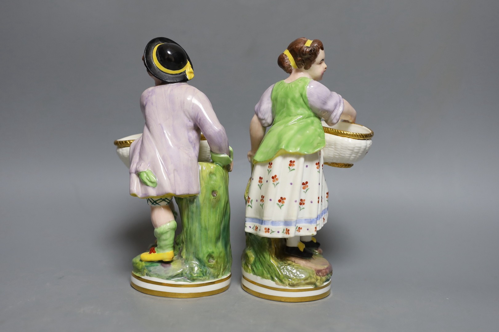 A pair of Victorian Minton's bone china figures holding baskets, 20cms high.